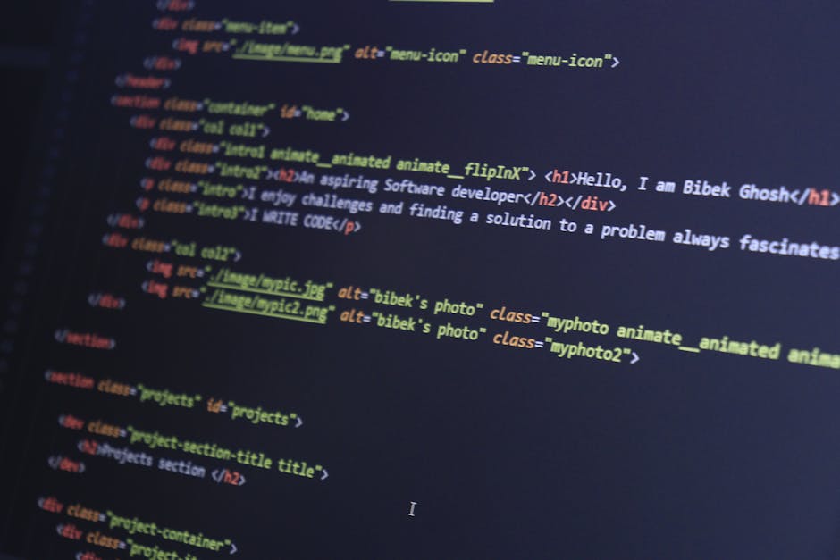 A close-up view of a laptop computer displaying lines of colorful programming code on its screen, placed on a wooden desk. Next to the laptop, there is a ceramic coffee mug with a partially visible in